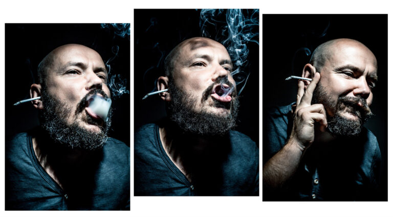 Mężczyzna z twarzą w cieniu pali papierosa