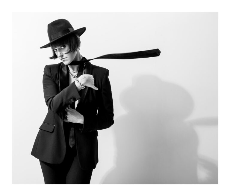 Kobieta w kapeluszu i z krawatem na jasnym tle