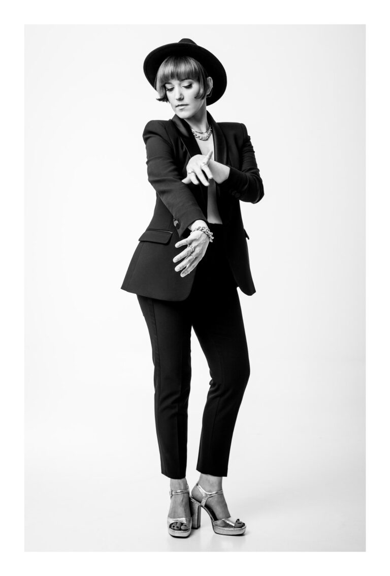 Kobieta w eleganckiej pozie w czarnym ubraniu patrzy w obiektyw