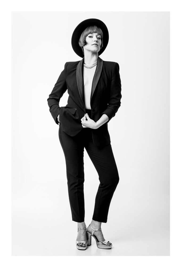 Kobieta w eleganckiej pozie w czarnym ubraniu patrzy w obiektyw