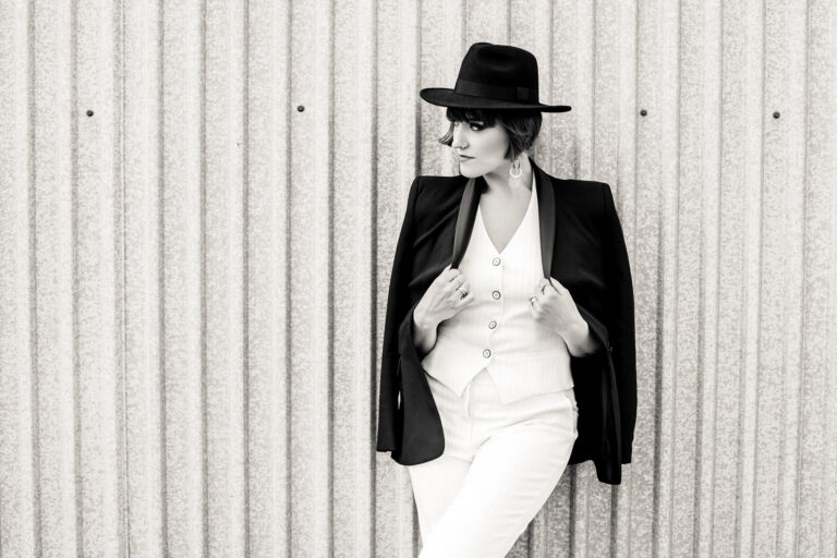 Kobieta przy ścianie patrzy w obiektyw